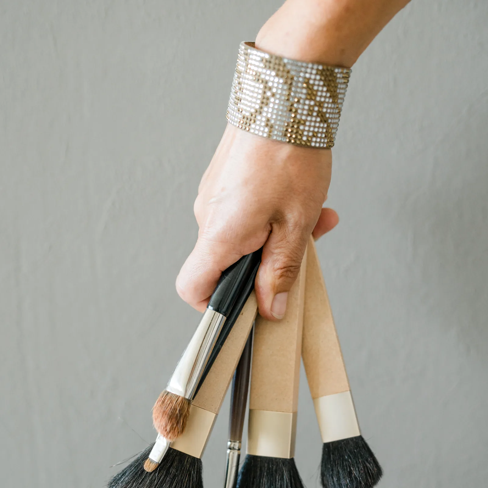 Kosmetikpinsel in der Hand.